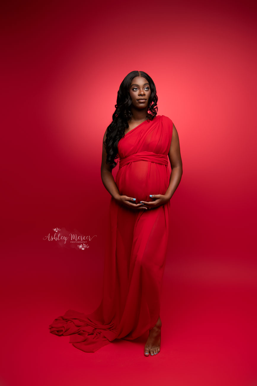 An eye catching red background paired with red fabric used a wrap dress on a very pregnant lady. She stands out against the red in this vibrant setting
