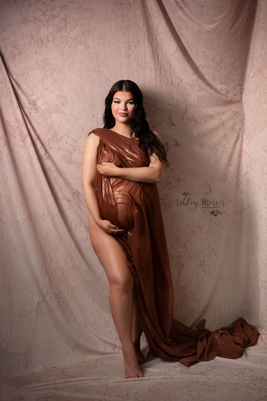 A sultry mom to be is showing off her leg while draped in sheer fabric.